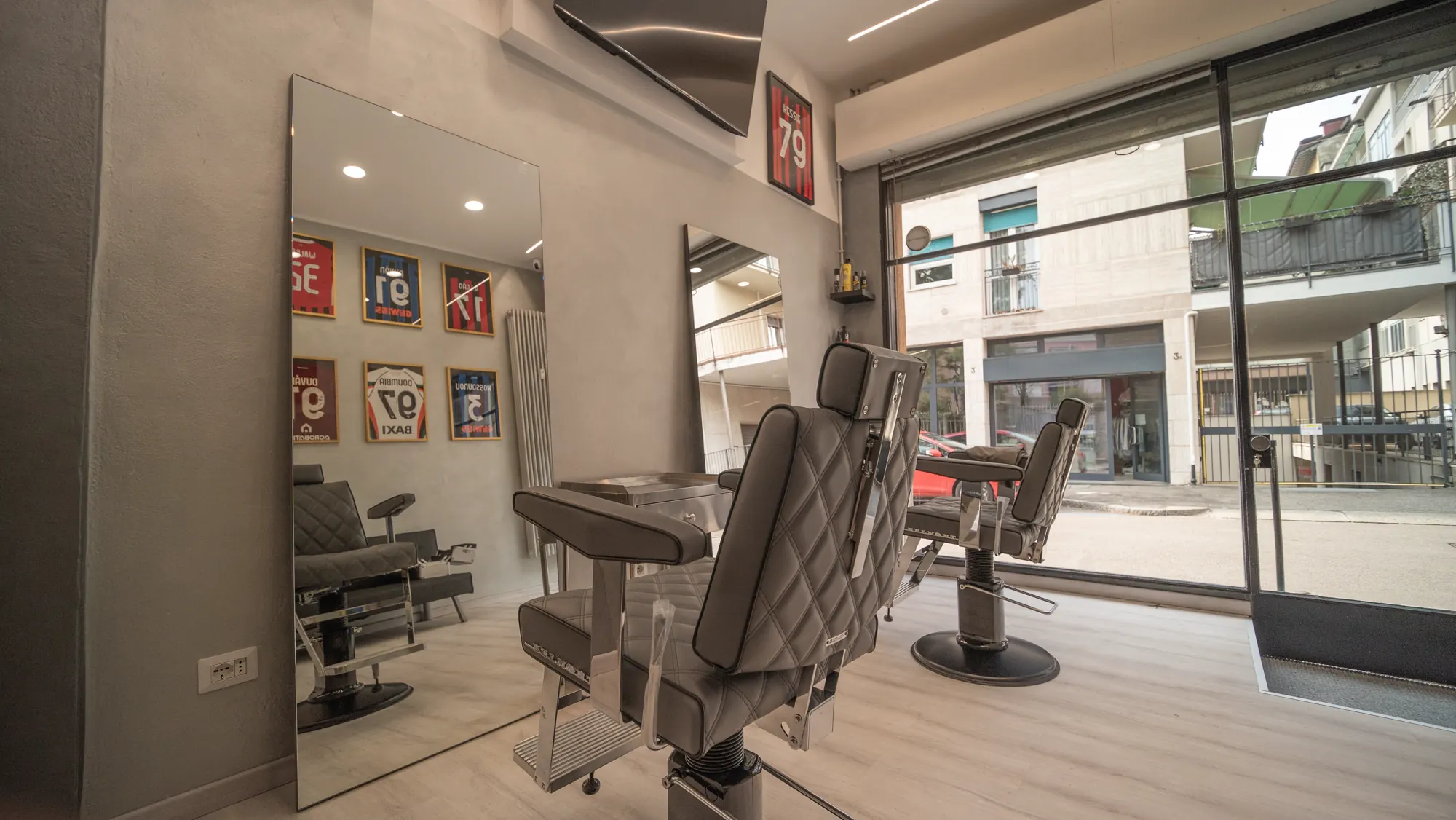 Interno di Hermann Barbershop: poltrone, specchi e maglie incorniciate